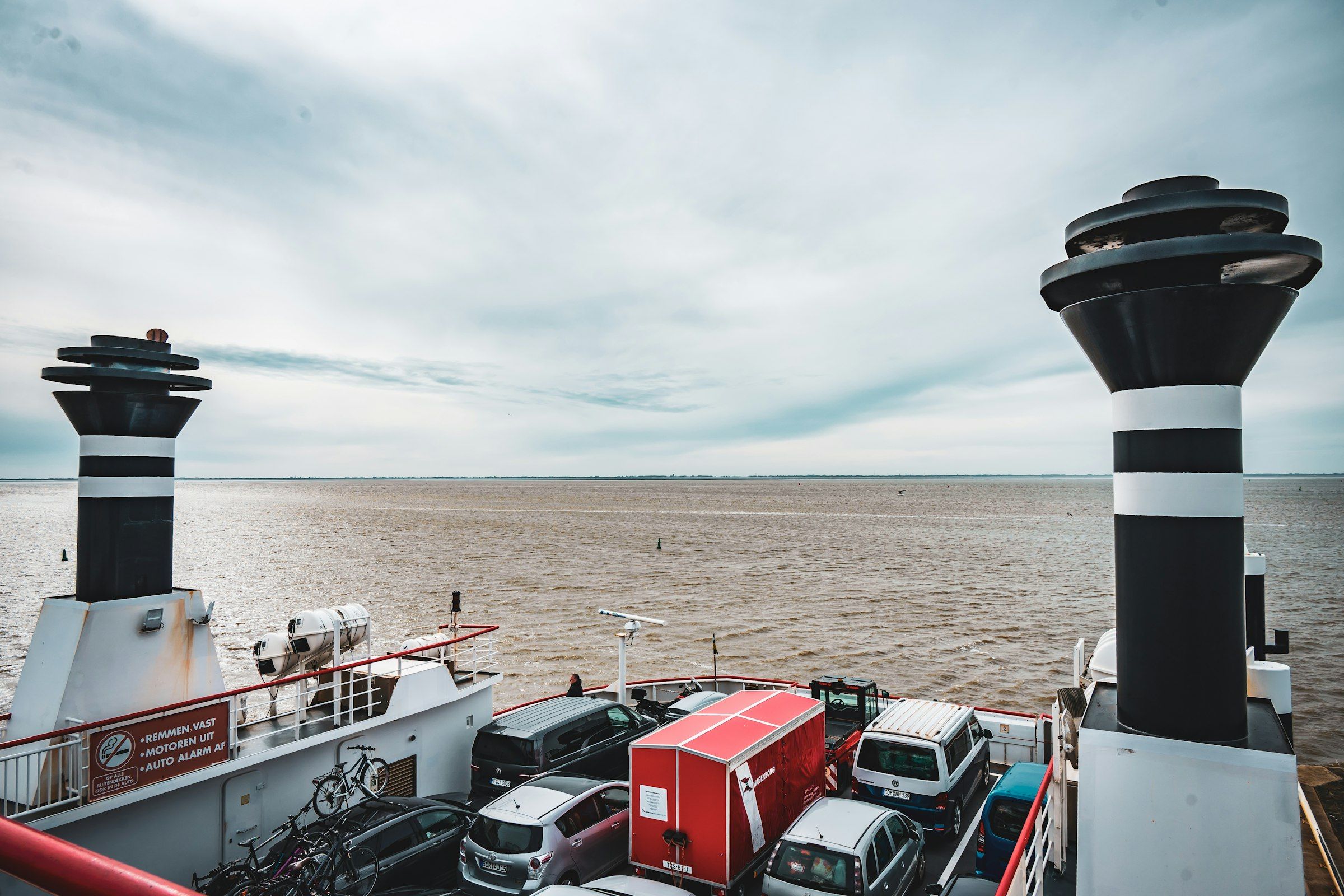 Cars parked on a ferry deck beneath the ship's funnels