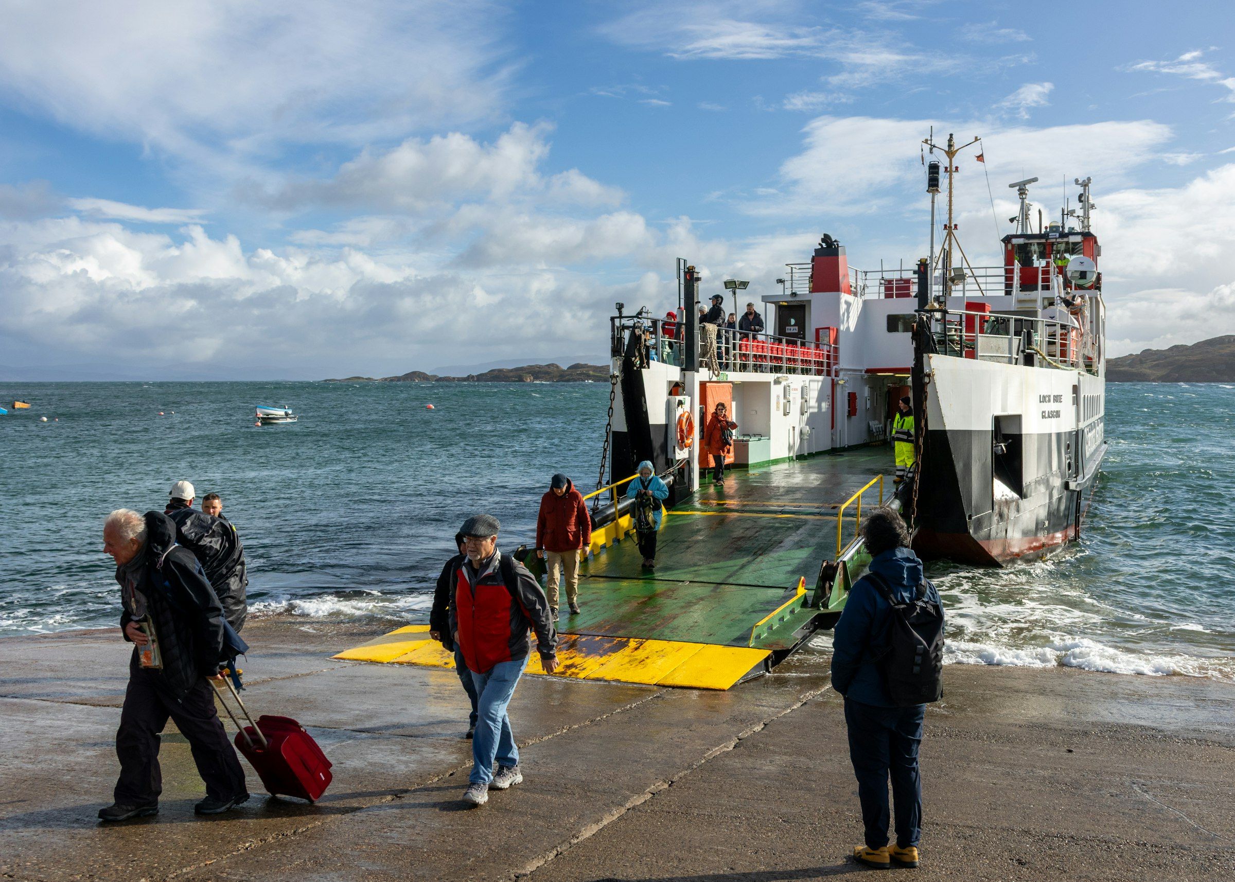 Passengers walking off a vehicle ferry onto a wet ramp