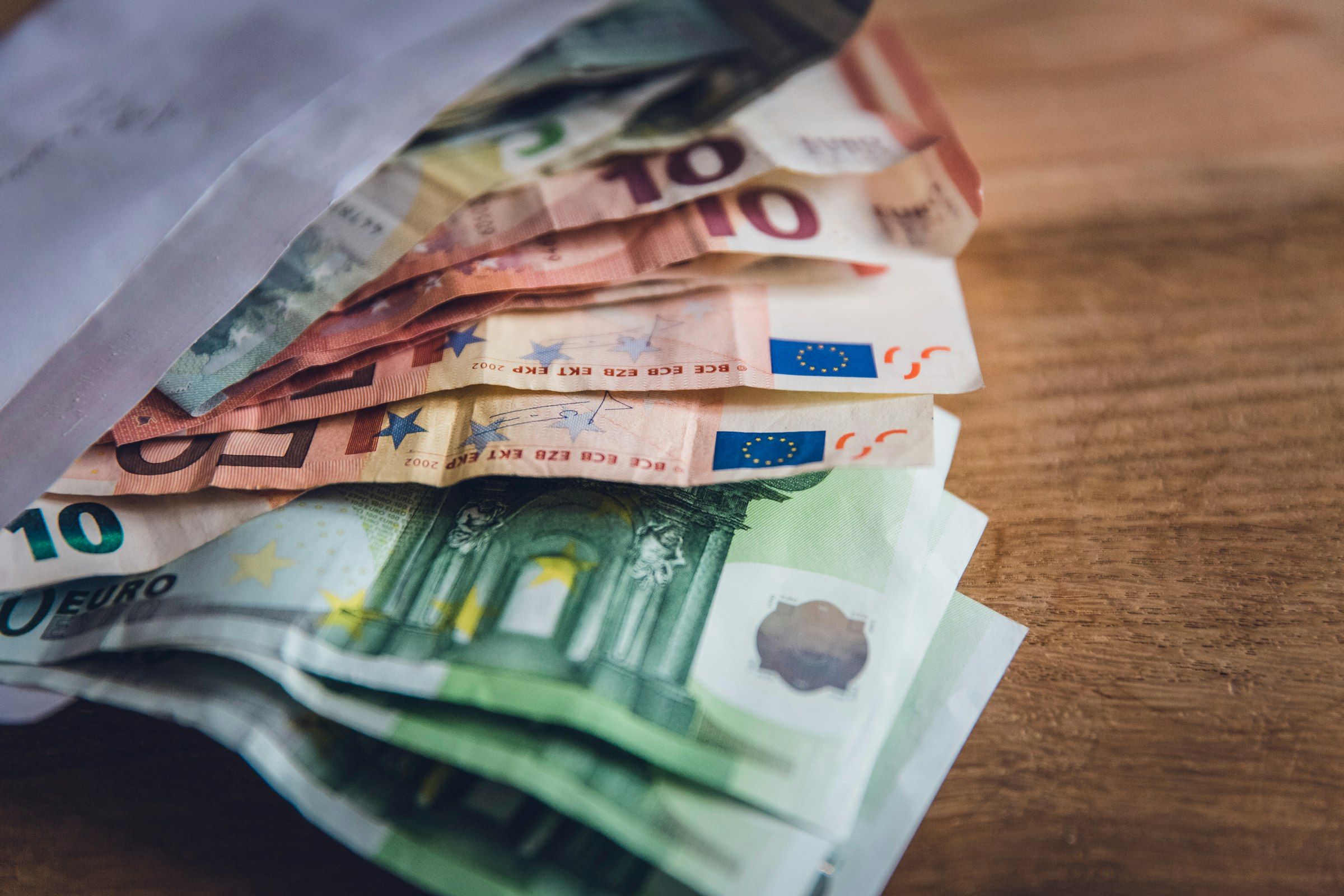 Euro banknotes spread on a wooden surface