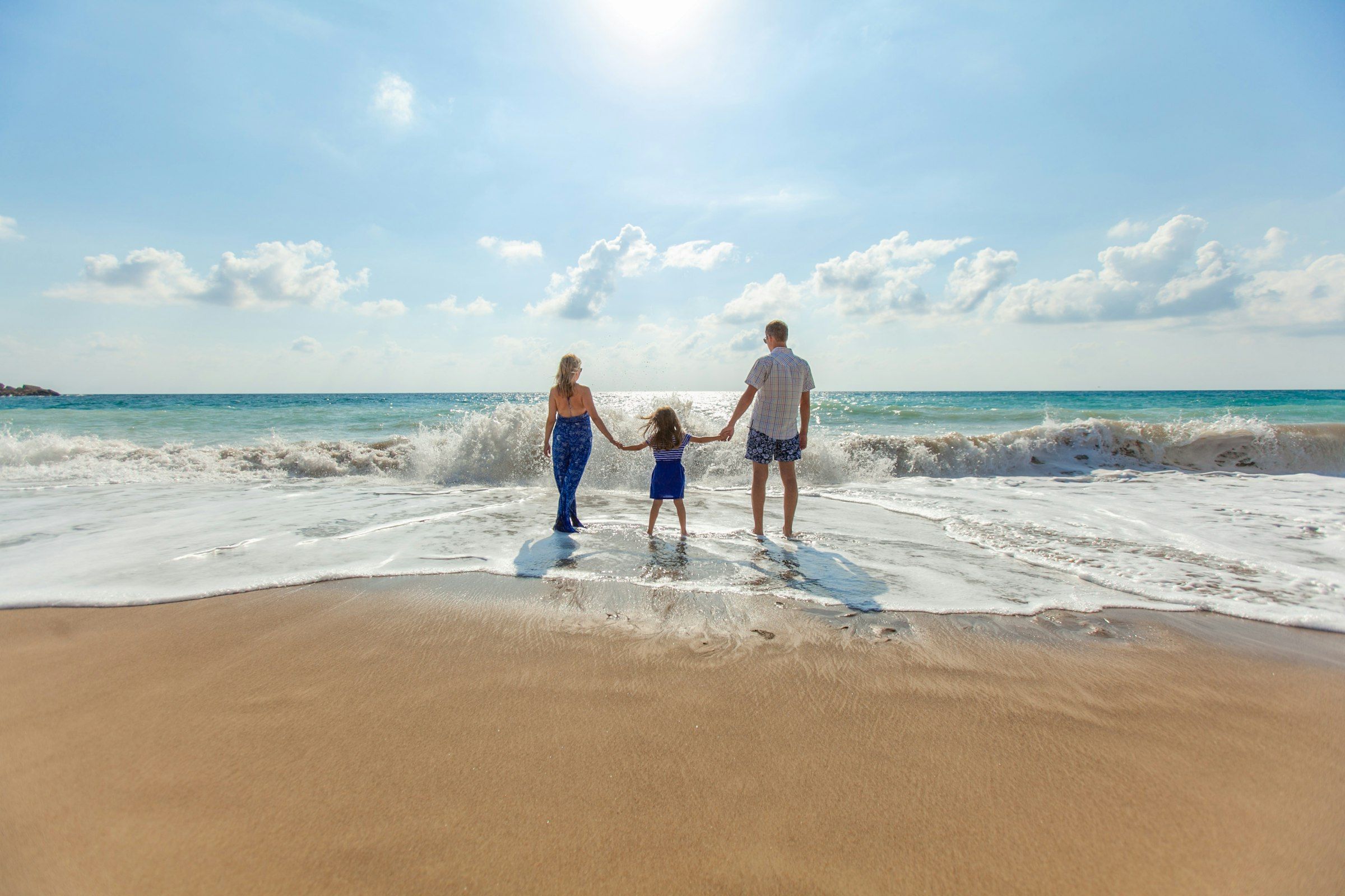 A man, a woman and a child holding hands on the seashore