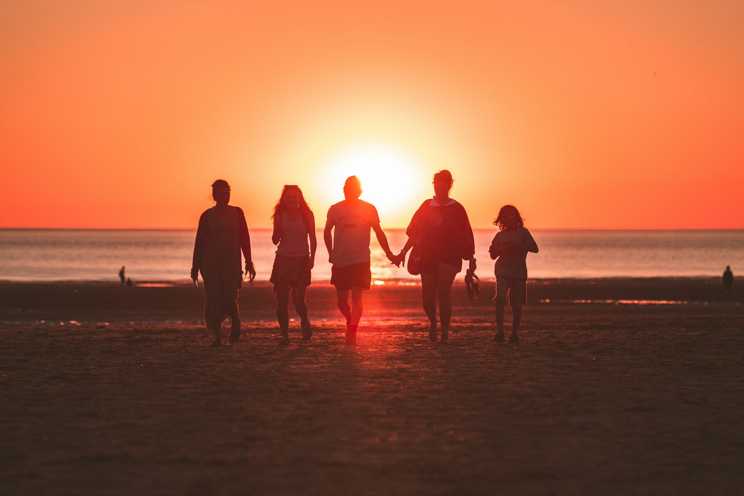 Silhouettes of a family walking along the shore at sunset