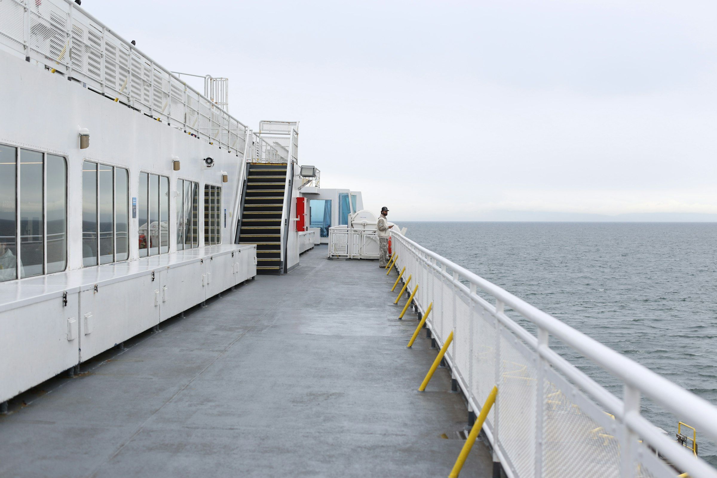A person on a ferry deck looking out over the sea