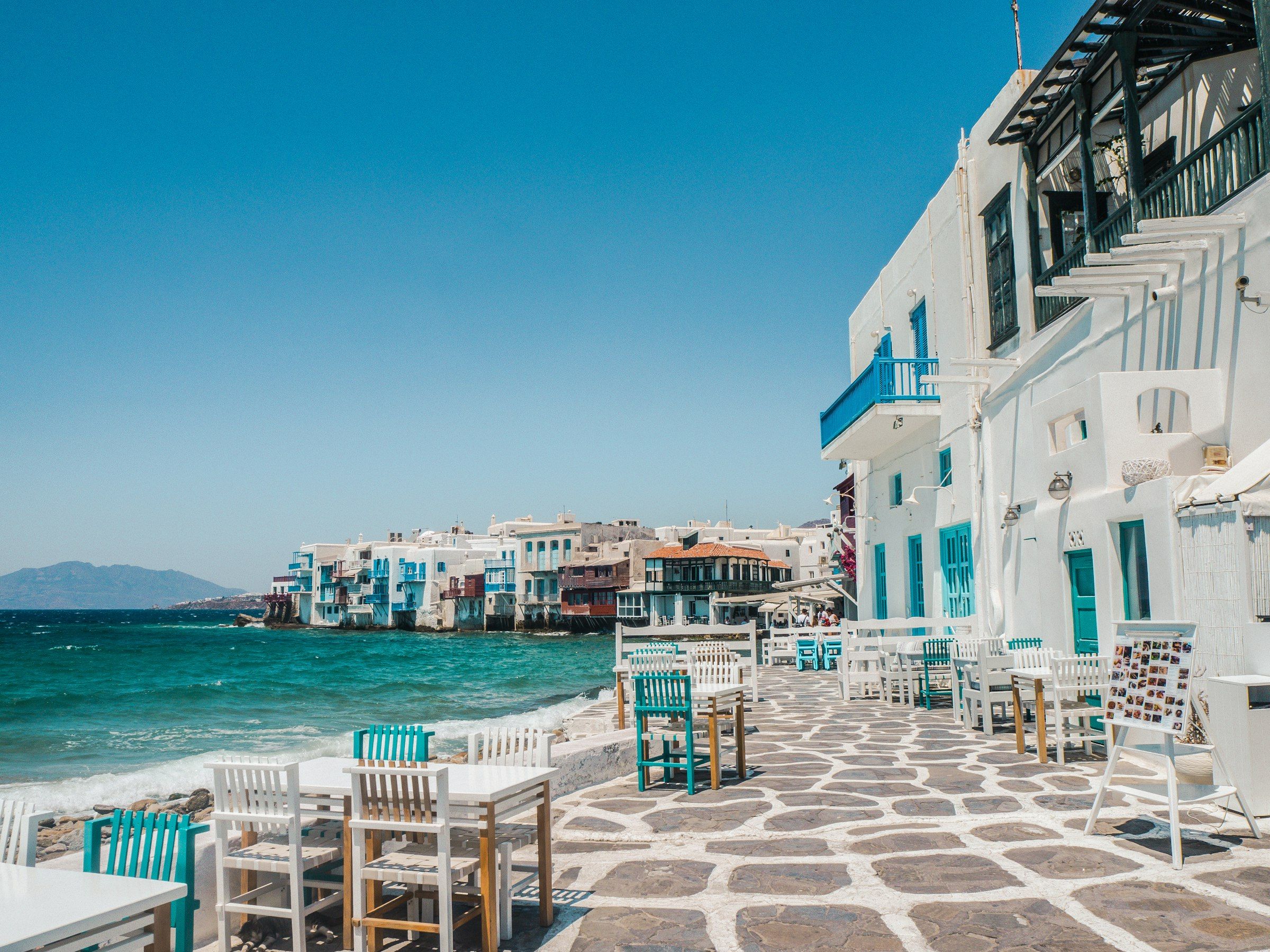 Tables and chairs on a stone patio beside the sea