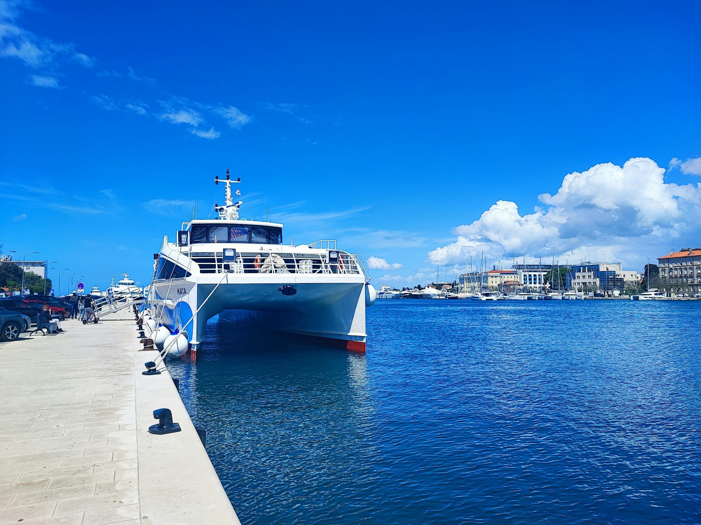 A catamaran ferry docked at a sunny waterfront