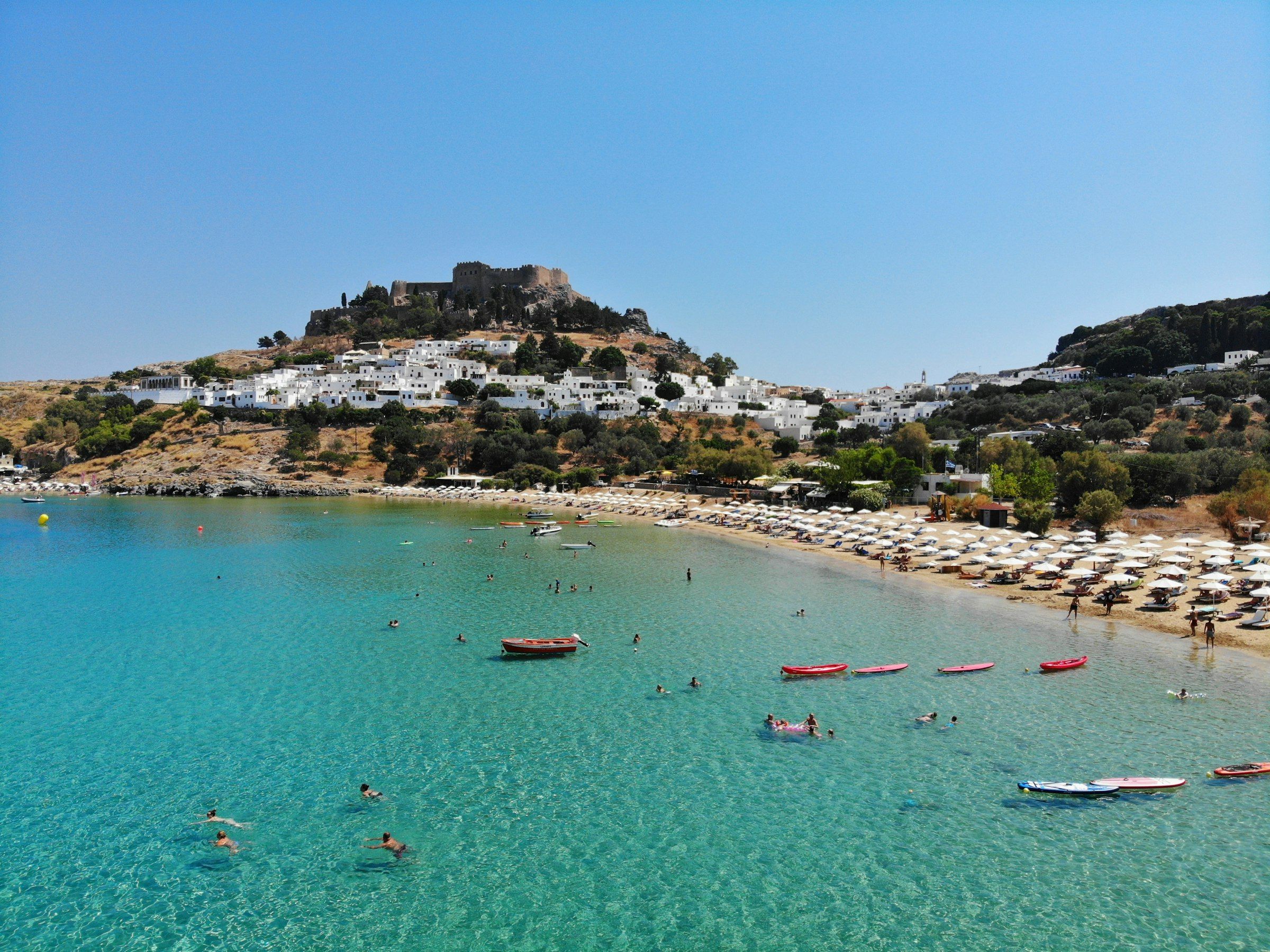 Ein Boot auf dem Meer unterhalb der Hügel von Lindos, Rhodos